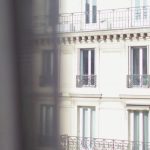 El Born Stay - Hotel with elegant balconies and bay windows in Paris as seen from opposite building through slightly ajar window curtains on sunny day